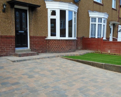 Block paved driveway with a small landscaped garden area.