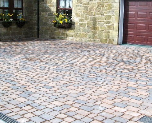 block paved driveway with a small lanscaped garden area
